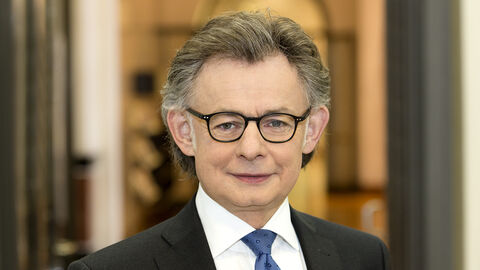 Regierungssprecher Michael Bußer Michael Bußer lächelt frontal in die Kamera. Er ist bis zur Brust zu sehen, trägt ein weißes Hemd, ein schwarzes Sakko und eine blaue Krawatte.