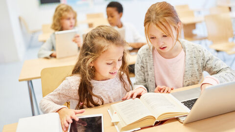 Zwei Mädchen in der Schule über Buch und PC Zwei Mädchen in der Schule über Buch und PC