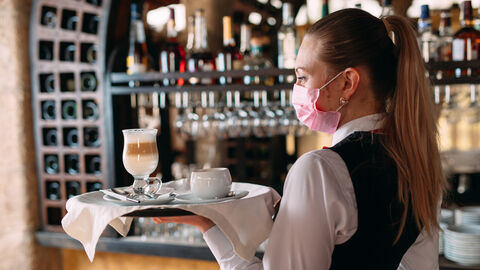Eine Kellnerin mit Maske und Tablett Eine Kellnerin mit Maske und Tablett