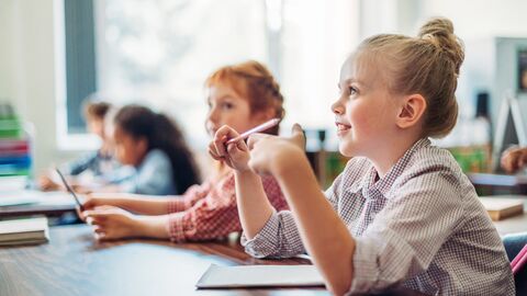Schule Kinder sitzen an einem Tisch und hören gespannt zu