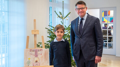 Dritter Platz für Jakobs Bild Der achtjährige Jakob steht mit Boris Rhein neben seinem gemalten Weihnachtsbild. Beide gucken in die Kamera