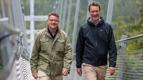 Hessens Ministerpräsident Boris Rhein und Nordrhein-Westfalens Ministerpräsident Hendrik Wüst wanderten gemeinsam vom nordhessischen Willingen ins südwestfälische Winterberg und besuchten dabei in der Nähe von Willingen die längste Hängebrücke Deutschlands, den „Skywalk“. Hessens Ministerpräsident Boris Rhein (links) und Nordrhein-Westfalens Ministerpräsident Hendrik Wüst (rechts) in der Nähe von Willingen auf der längsten Hängebrücke Deutschlands, dem „Skywalk“, auf die Kamera zulaufend