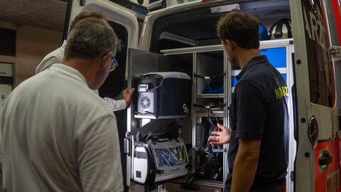 Ministerpräsident Rhein begleitet Einsatzfahrt Ministerpräsident Rhein steht vor dem geöffneten Einsatzwagen, zwei weitere Personen erklären Gerätschaften.