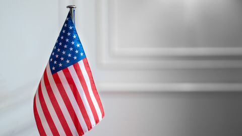 Amerikanische Flagge vor weißer Wand.