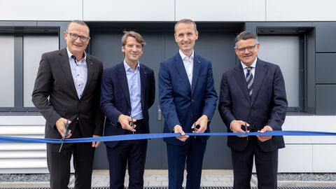 Ministerpräsident Boris Rhein bei der Eröffnung des neuen Reinraums der Firma Zeiss SMT in Roßdorf.  Vier Männer stehen in Anzügen gekleidet nebeneinander. Vor ihnen ist ein blaues Band gespannt, das sie mit einer Schere durchschneiden wollen.