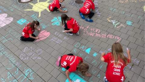 Schülerinnen und Schüler der Gönser Grundschule aus Butzbach malen Kreidebotschaften zum Thema Kinderrechte vor das Hessische Ministerium für Soziales und Integration