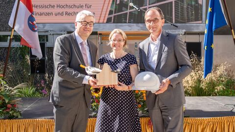 Karl Jennemann, Tanja Eichner und Michael Boddenberg übergeben einen Werkzeugkasten und Bauhelm.