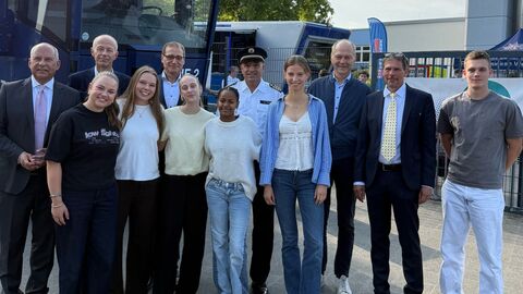 Mehrere Erwachsene sowie Schülerinnen und Schüler stehen vor Polizei-LKW